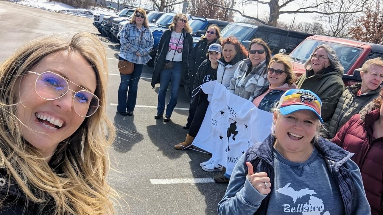 A woman drives a blue Ford Bronco up a rocky hill